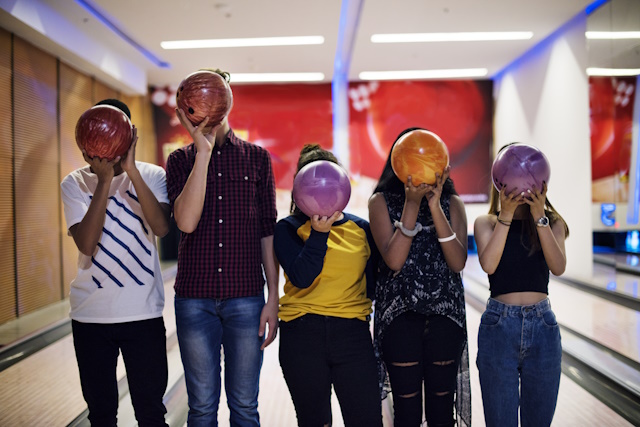 Personnes tenant des boules de bowling devant leurs visages.